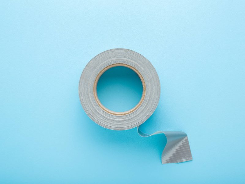 One roll of silver cloth duct tape on light blue table backgroun